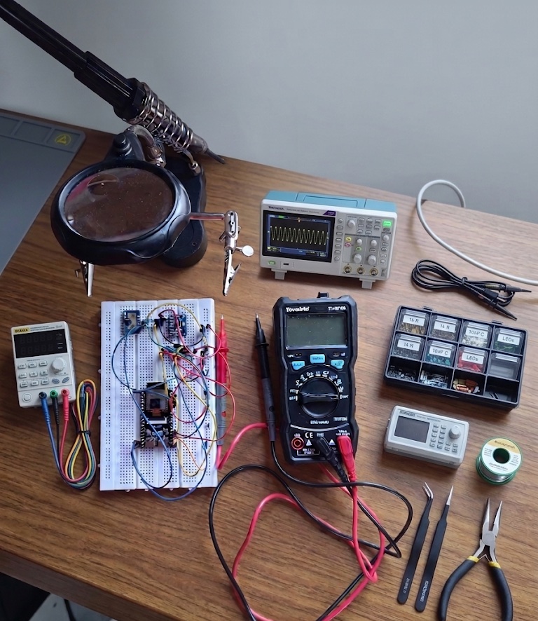 A workbench with a breadboard, oscilloscope, multimeter and hand tools